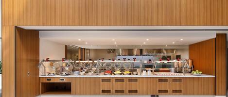 Un buffet moderne, doté de plusieurs présentoirs de nourriture, d’un espace de service central et d’un design épuré et contemporain.