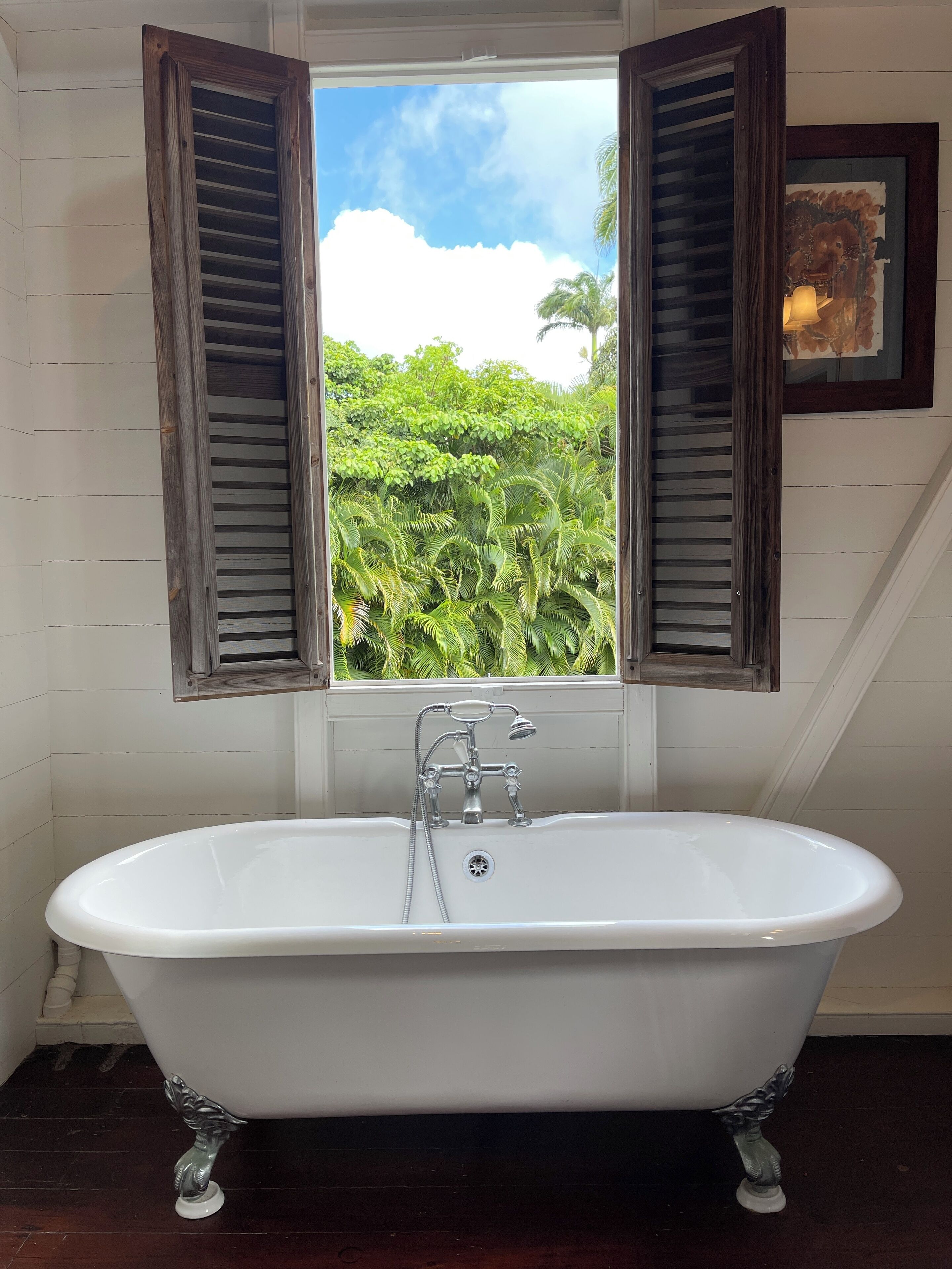 Una bañera independiente con una ventana que ofrece vistas a un exuberante follaje.