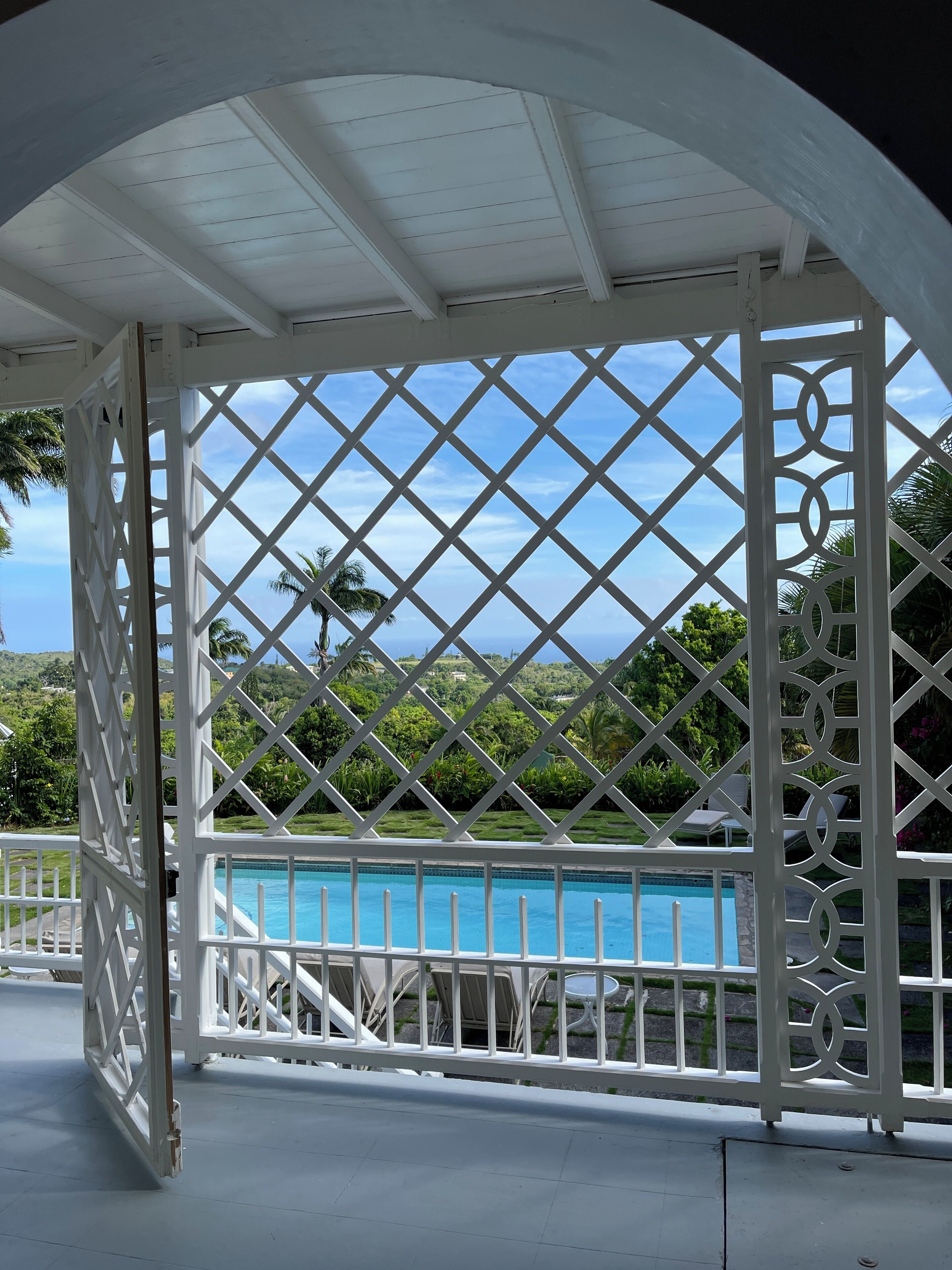 Un'area esterna coperta con piscina, struttura in lattice bianco e vista su un paesaggio verde e rigoglioso.