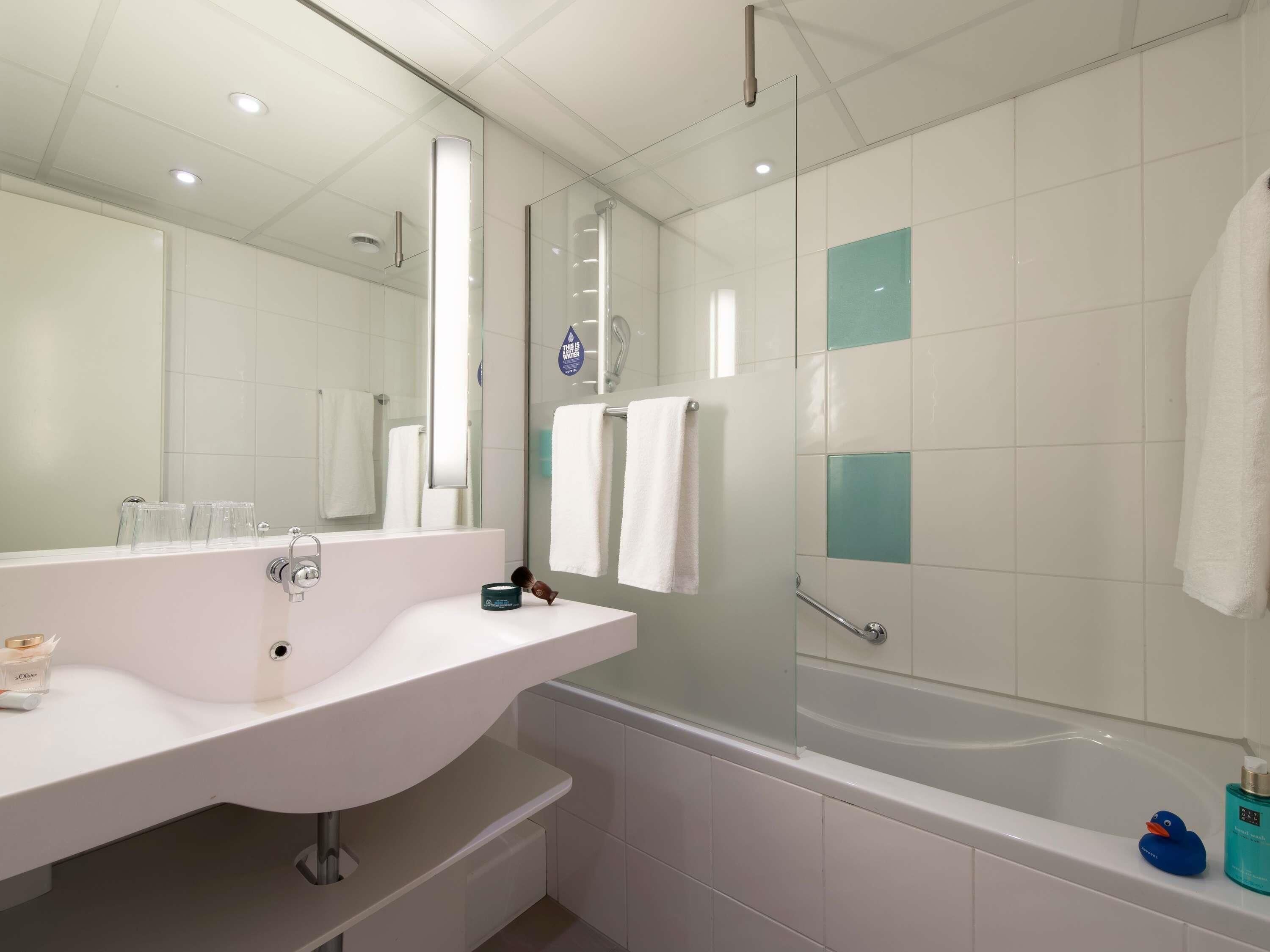 A modern bathroom with a white sink, mirror, and glass shower enclosure.