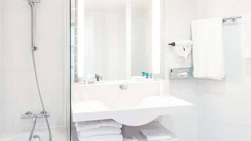 Un baño moderno con ducha de vidrio, lavamanos blanco y espejo.