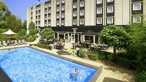 A hotel with a swimming pool, outdoor seating, and a clear blue sky. - Novotel Maastricht (Maastricht)