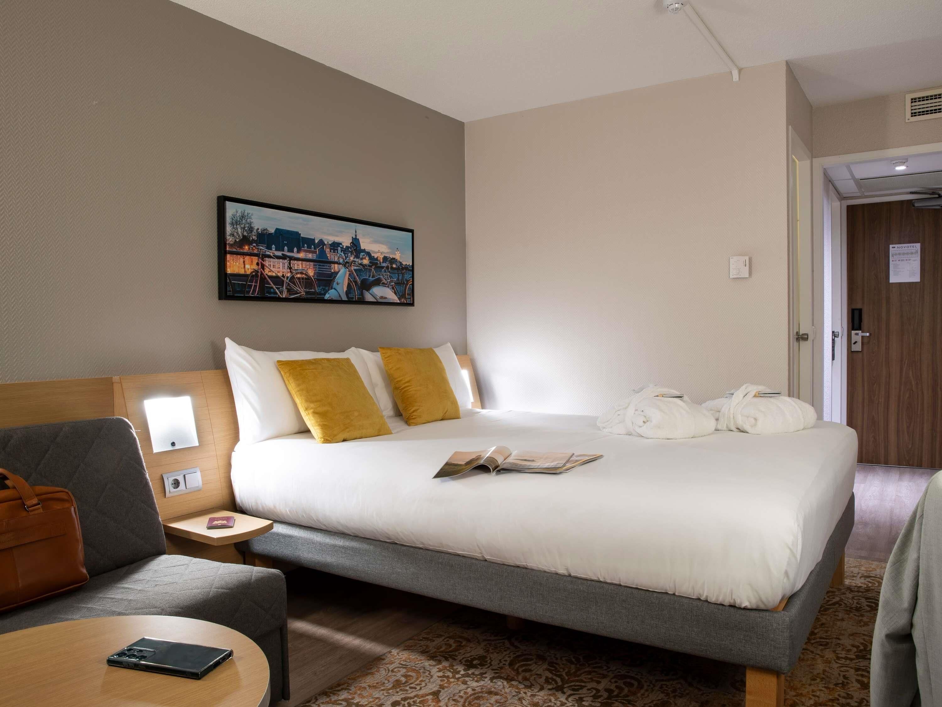 Une chambre d’hôtel avec un lit, une chaise, une table, un tableau et une porte.