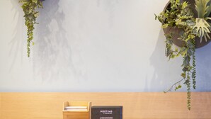A wall-mounted planter with hanging plants, a Samsung dishwasher, and a wooden cabinet below. - Novotel Maastricht (Maastricht)