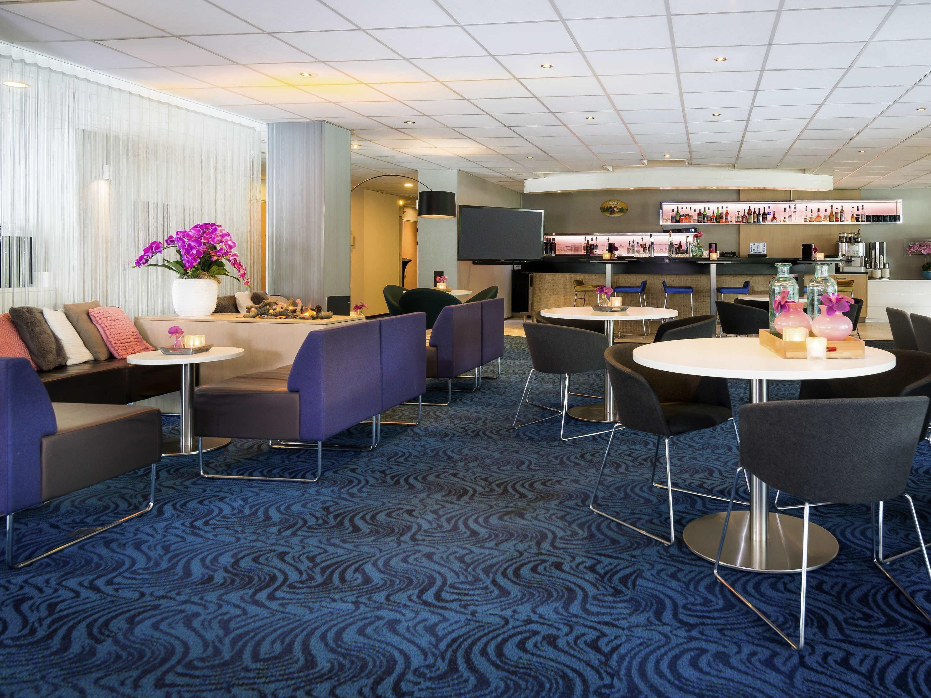 A hotel lobby with seating areas, a bar, and a reception desk.