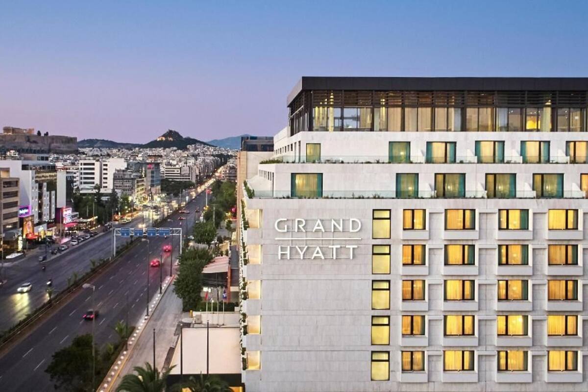 Un hôtel Grand Hyatt à l’architecture moderne, avec de nombreux étages et une vue sur une rue animée où circulent de nombreux véhicules.