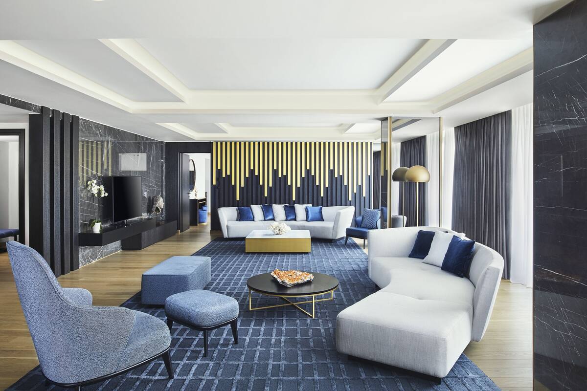 Un salon moderne avec un canapé blanc, des fauteuils bleus et une table basse.