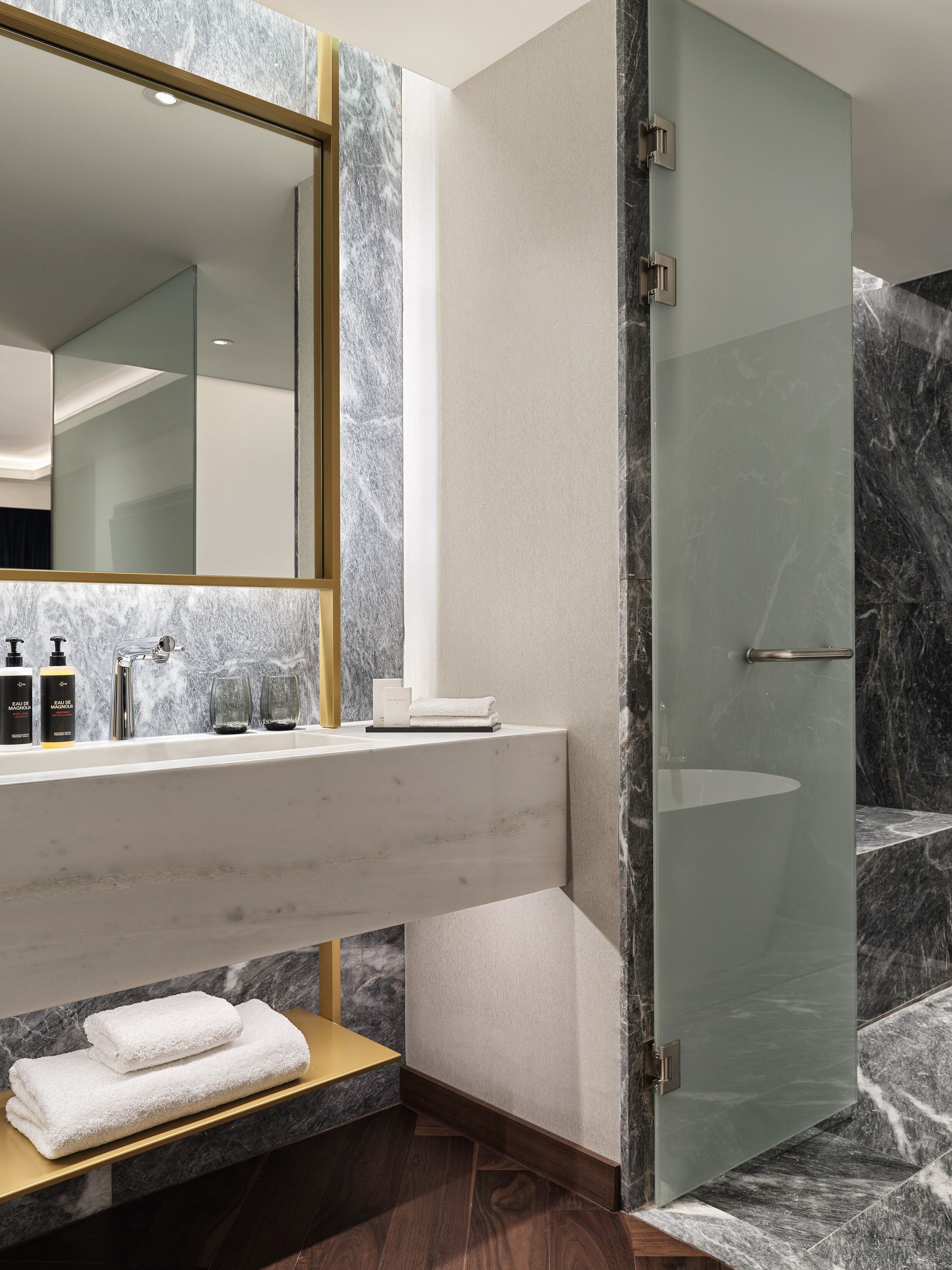 A modern bathroom with a marble vanity, a glass shower enclosure, and a large mirror.