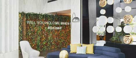A modern lobby with a blue sofa, a white armchair, and a gold coffee table.