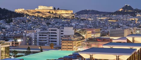 A hotel with a rooftop pool, modern architecture, and views of ancient ruins.