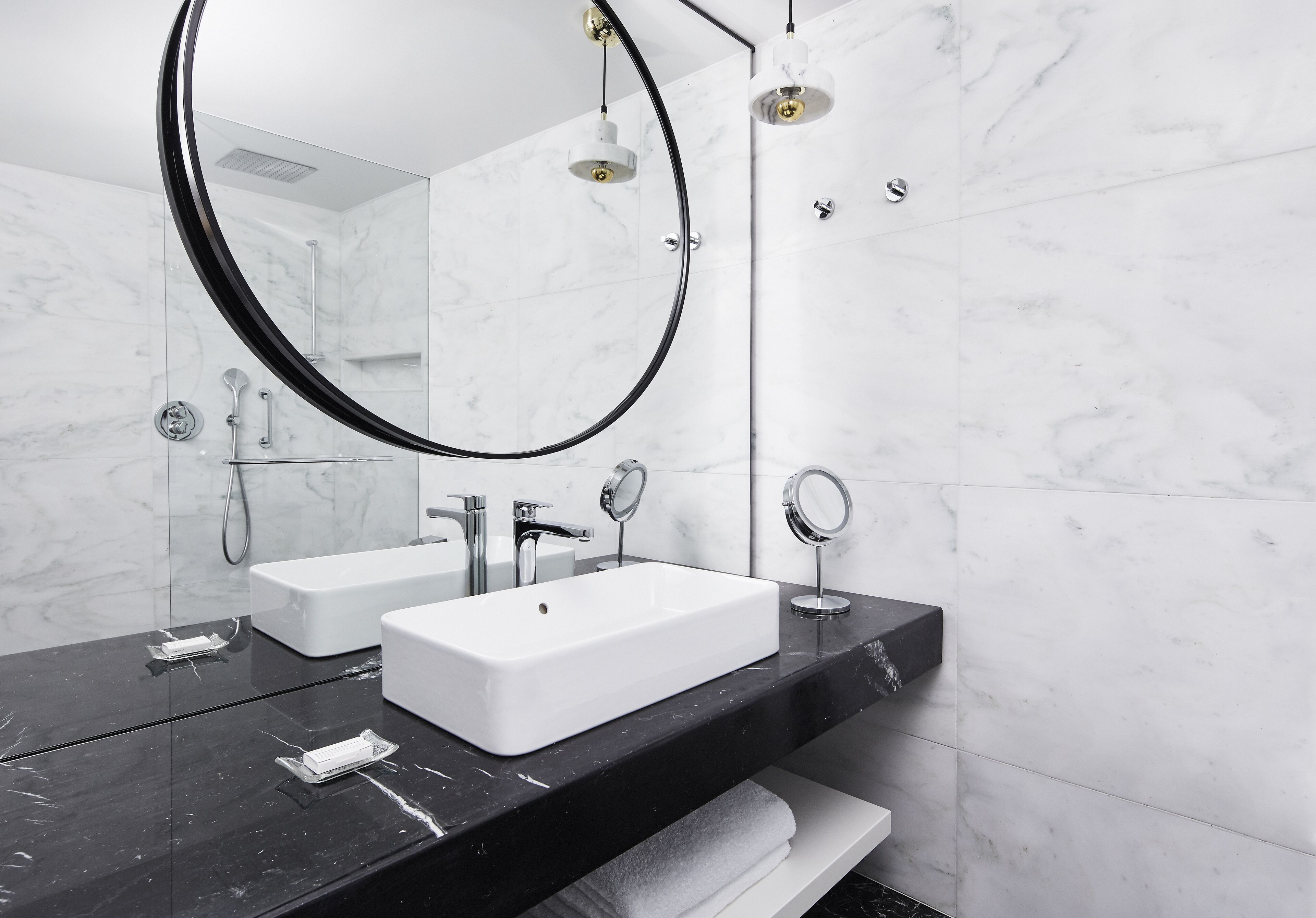 Un baño moderno con encimera de mármol negro, lavamanos blanco y un espejo grande.
