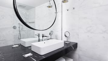 Une salle de bain moderne avec un comptoir en marbre noir, un lavabo blanc et un grand miroir.