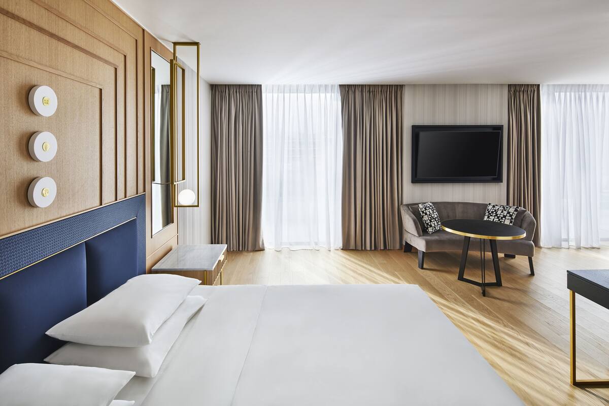Une chambre d’hôtel avec un grand lit, une télévision, un canapé et une petite table.
