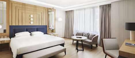A hotel room with a large bed, a sofa, a small round table, and a chair.