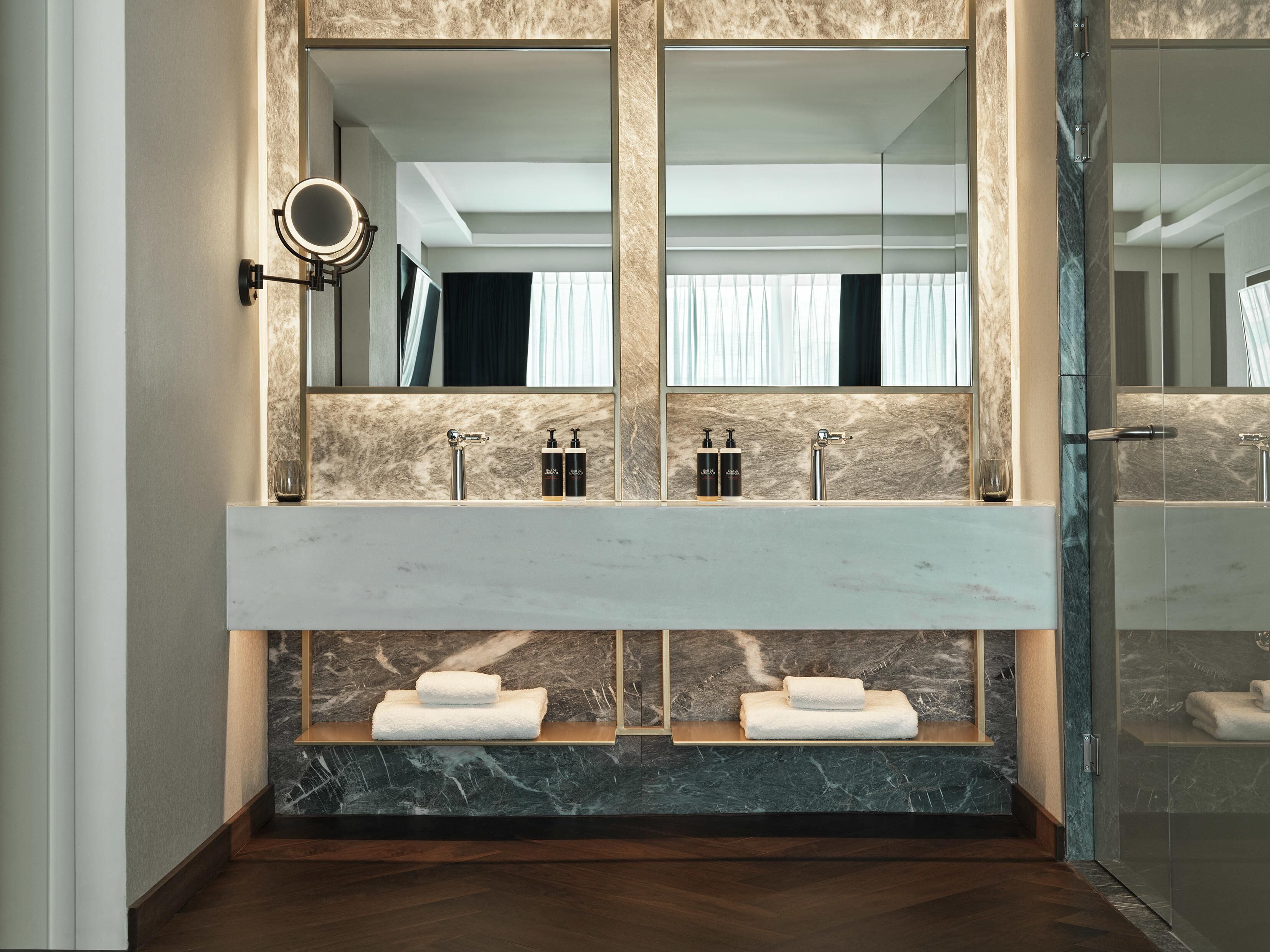 A modern bathroom with a large mirror, dual sinks, and a glass-enclosed shower.
