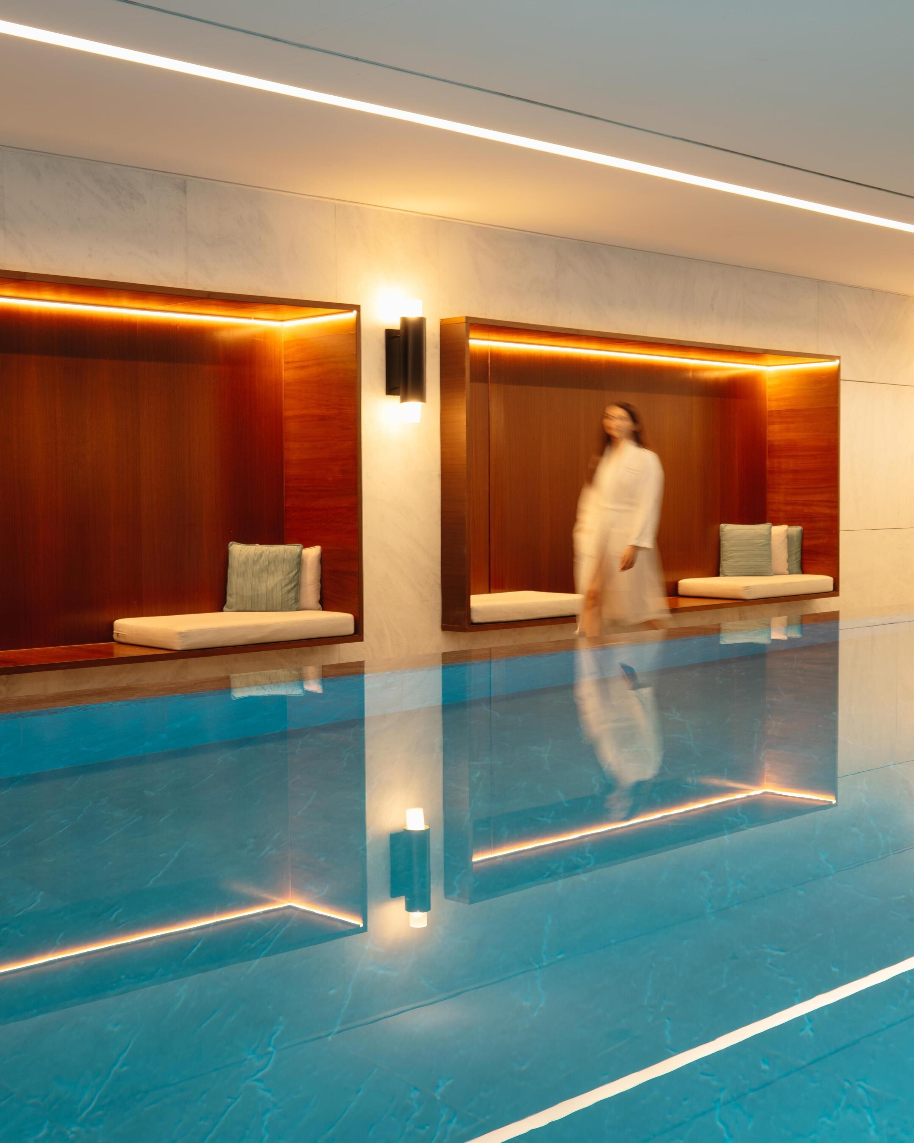 Un moderno vestíbulo de hotel con piso reflectante, paneles de madera y zonas de estar.