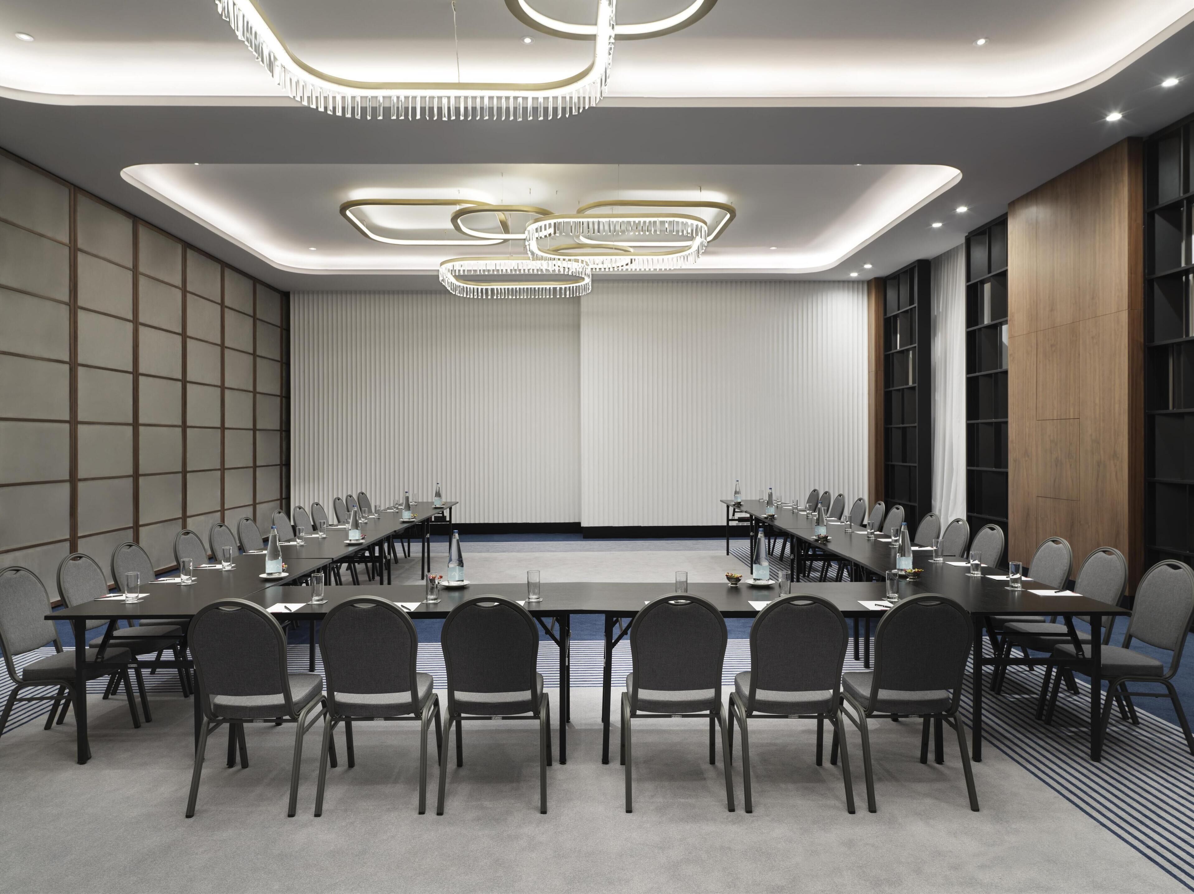 Un salón de conferencias con una larga mesa, sillas e iluminación moderna.
