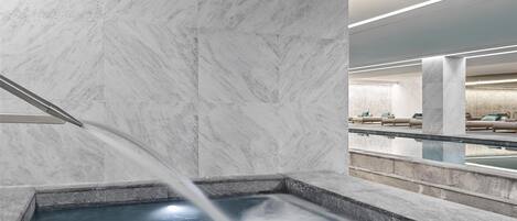 A modern spa area with a marble wall and a hot tub.