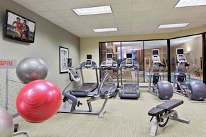 A gym with treadmills, elliptical machines, and exercise balls.