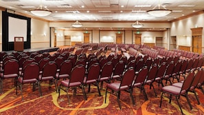 A conference room with rows of chairs, a stage, and a podium.