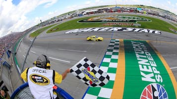 Une piste de course avec un drapeau à damier, une voiture et une personne tenant un drapeau.