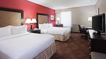 Una habitación de hotel con dos camas, un escritorio, una televisión y una silla.