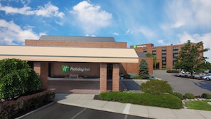 A Holiday Inn hotel with a brick facade, a covered entrance, and a parking lot. - Holiday Inn Cincinnati Airport by IHG (Hebron)