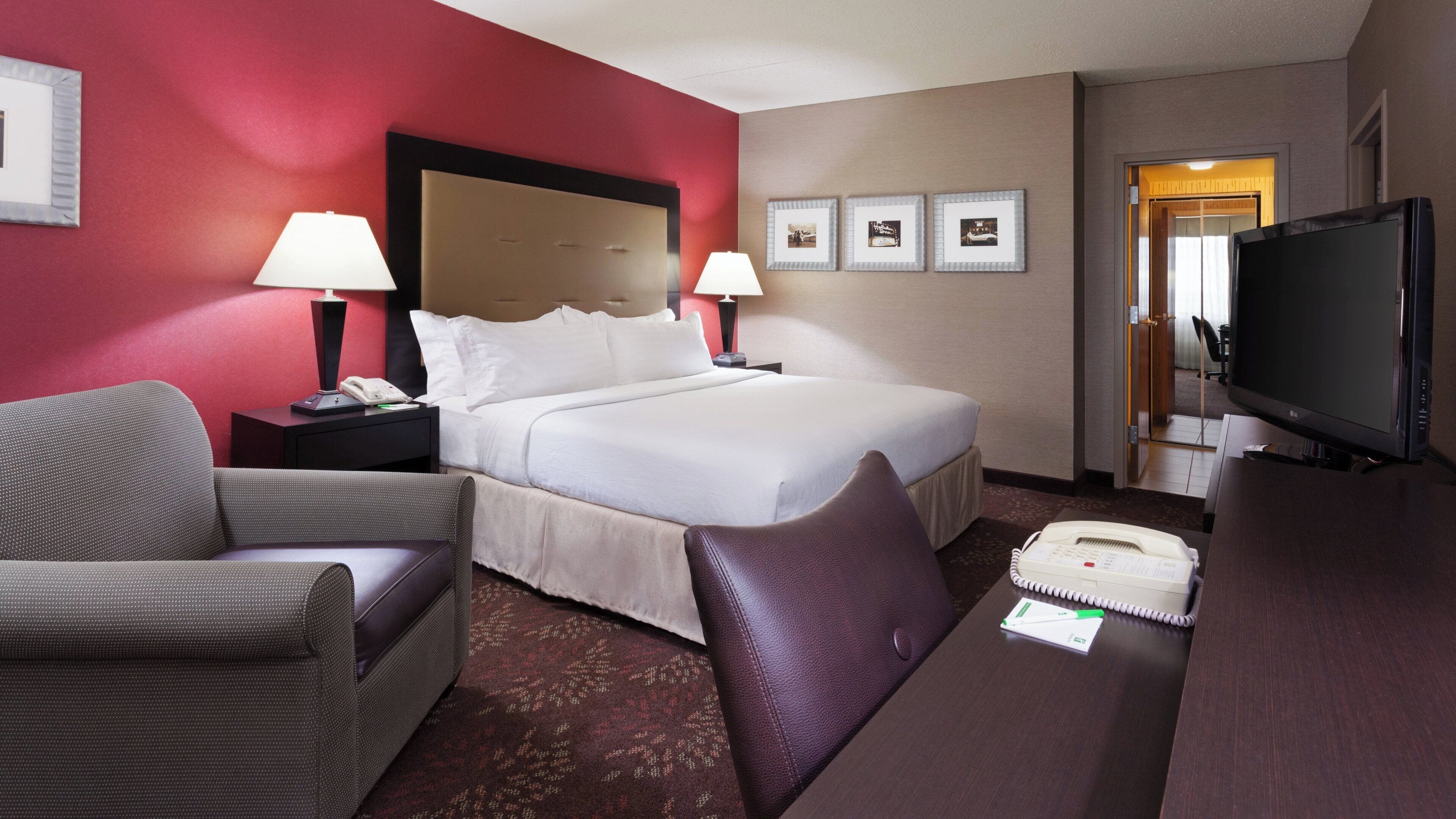 Habitació d'hotel amb un llit, dues làmpades de nit, una televisió, un escriptori amb un telèfon i una cadira.