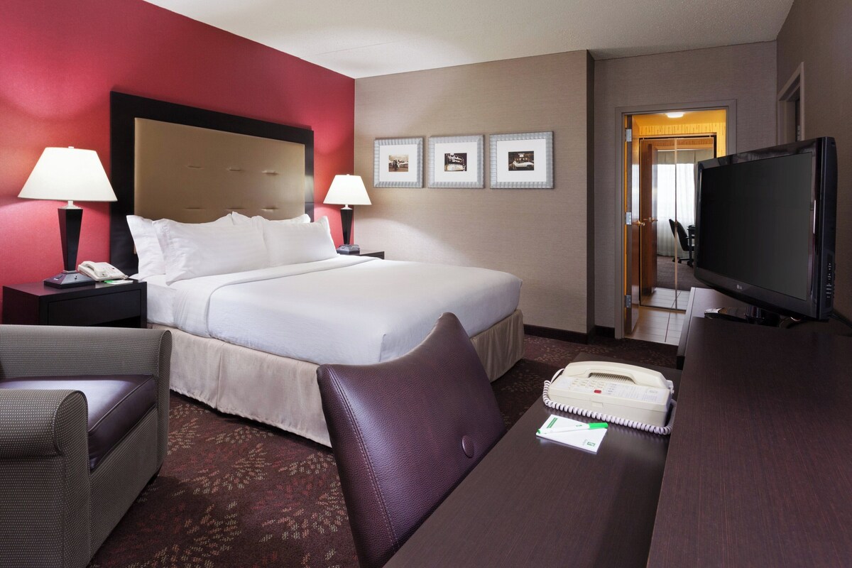 Une chambre d’hôtel comprenant un lit, deux lampes de chevet, une télévision, un bureau avec un téléphone et une chaise.