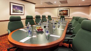 A conference room with a long table, green chairs, water bottles, and framed pictures on the walls. - Holiday Inn Cincinnati Airport by IHG (Hebron)
