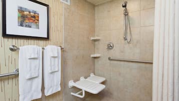 A shower area with a grab bar, a white towel rack, and a framed picture on the wall.