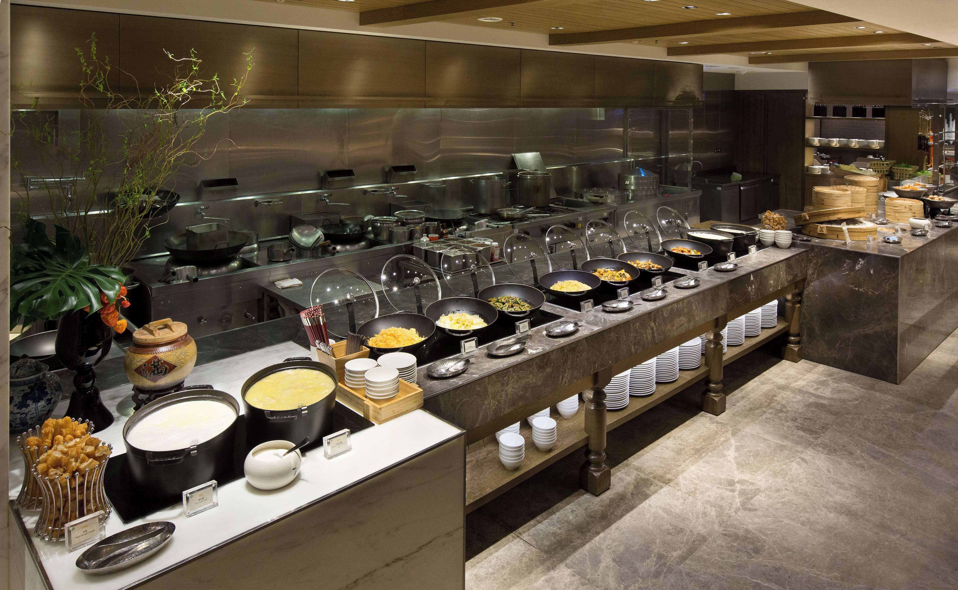 A buffet setup with various food stations and a large kitchen area in the background.