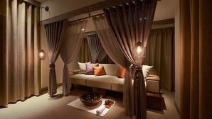 A cozy bedroom with a sofa, a bedside table, a lamp, and a decorative bowl on the floor. - Grand Hyatt Taipei (Taipei)