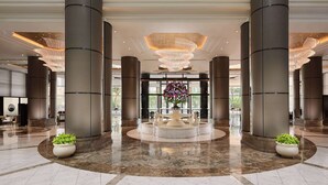 A spacious lobby with large columns, a central fountain, and a modern chandelier. - Grand Hyatt Taipei (Taipei)