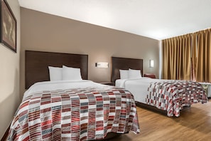 A hotel room with two beds, each with a wooden headboard, white bedding, and a red and white checkered blanket. - Red Roof Inn Montgomery - Midtown (Montgomery)