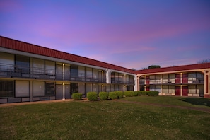 A multi-story motel with a red roof, balconies, and a grassy courtyard. - Red Roof Inn Montgomery - Midtown (Montgomery)