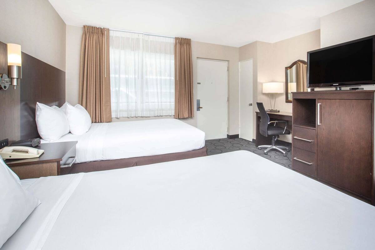 Una habitación de hotel con una cama grande, un escritorio con teléfono, televisión y armario.