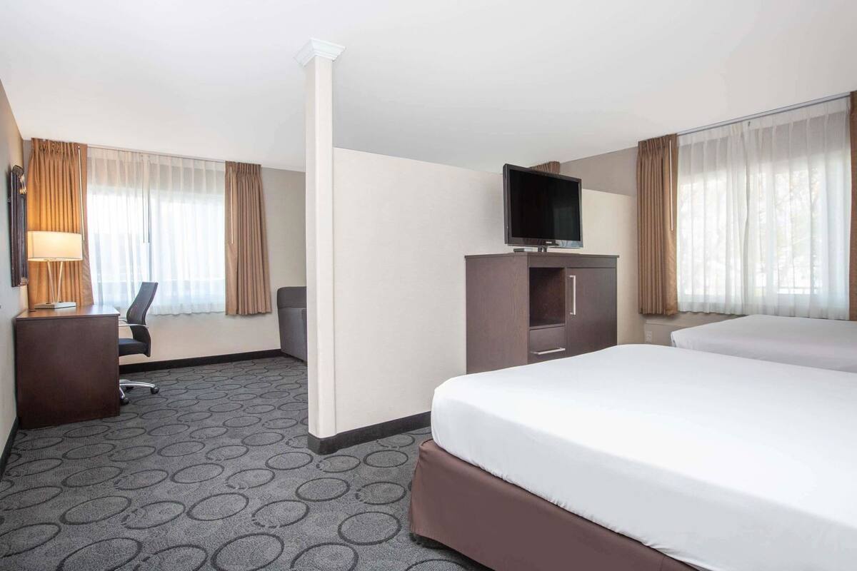 Una habitación de hotel con cama, escritorio, silla, televisor y armario.