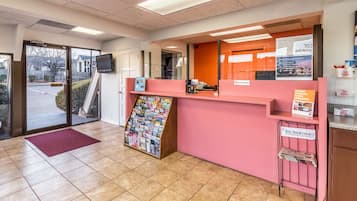 A reception area with a pink counter, a bulletin board, and a magazine rack.