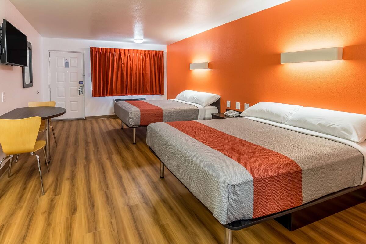 A hotel room with two beds, a desk, and a chair.