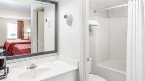 Un baño de hotel con un lavabo blanco, un espejo, una ducha y un inodoro.