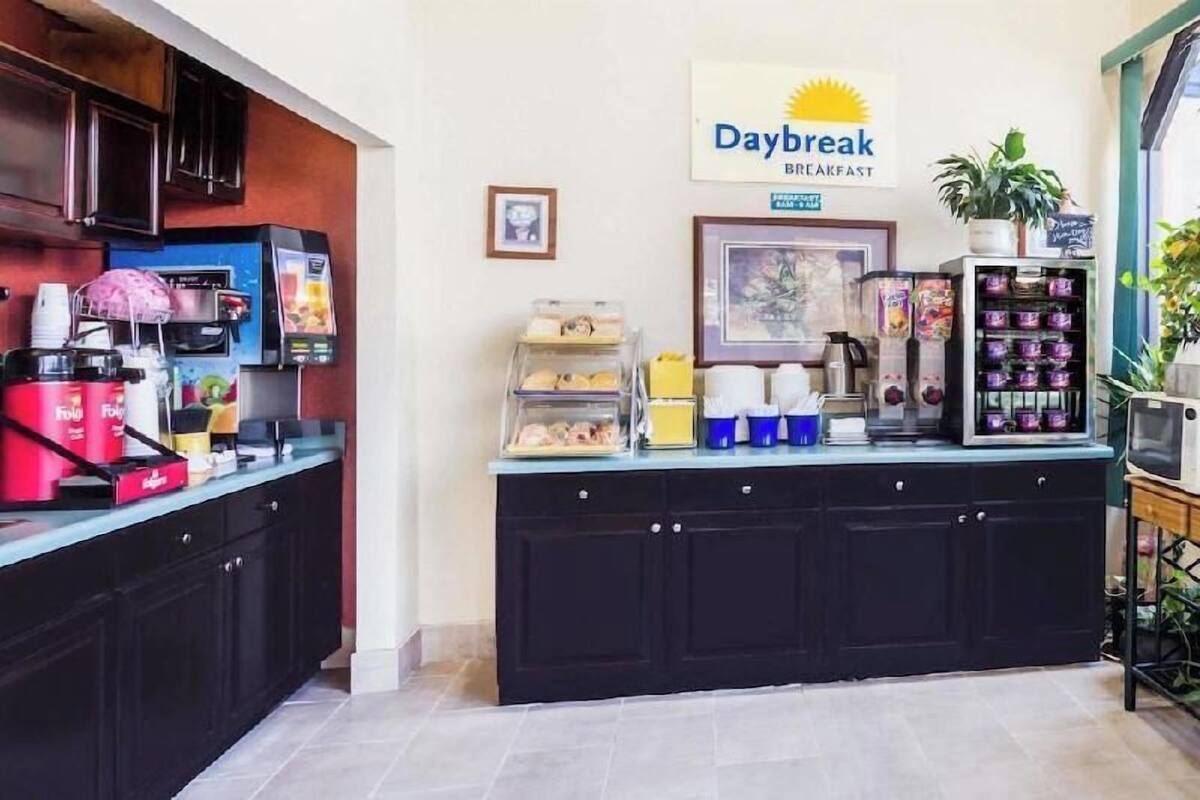 A breakfast counter with coffee machines, a Daybreak sign, and a variety of food items.