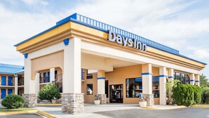 Un hotel Days Inn con fachada color beige, detalles azules y entrada cubierta.