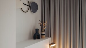A modern bedroom with a white bed, a bedside lamp, and a shelf with decorative items. - Conscious Hotel Museum Square (Amsterdam)