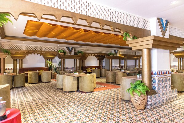 Un vestíbulo amplio con suelo estampado, varias zonas de estar y columnas decorativas.