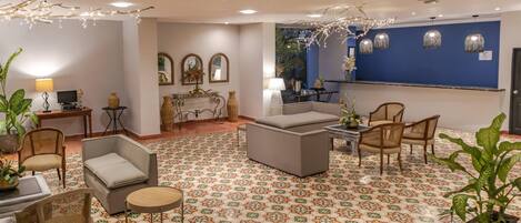 Un vestíbulo de hotel con pisos estampados, arreglos de asientos y elementos decorativos.