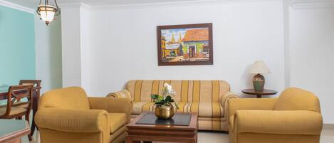 Una sala de estar con un sofá, dos sillones, una mesa de centro y un cuadro en la pared.
