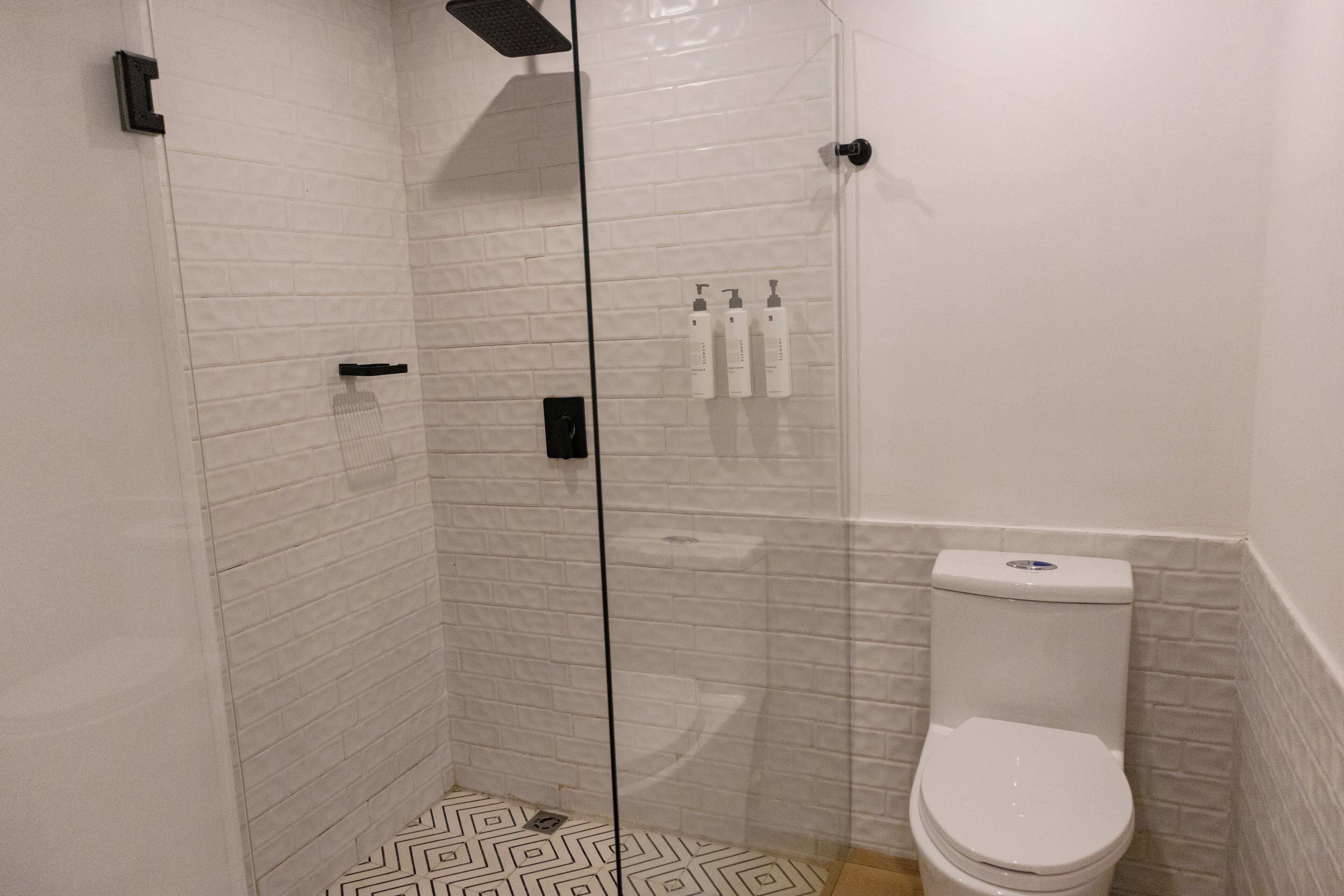 A bathroom with a glass-enclosed shower, a white toilet, and a patterned floor.