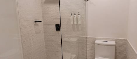 Une salle de bain avec une douche à parois de verre, des toilettes blanches et un carrelage décoratif.