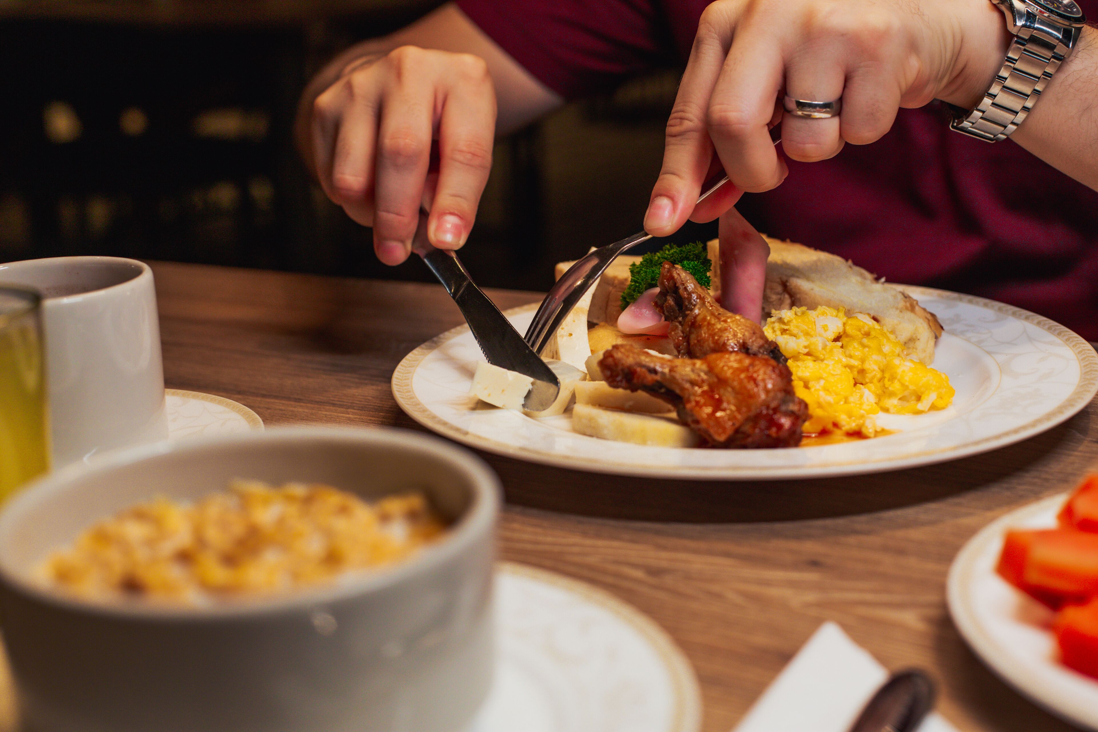 A person cutting food with a knife and fork.